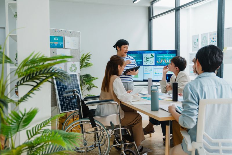 A group of coworkers discuss renewable energy solutions, emphasizing sustainable business practices in a modern office setting. ESG sustainable business office concept.