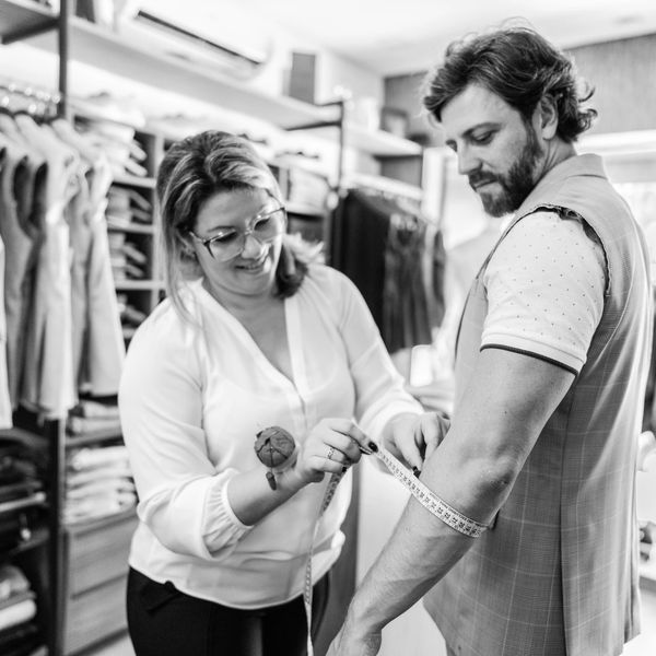 A tailor measuring a man's arm for a custom suit fitting.