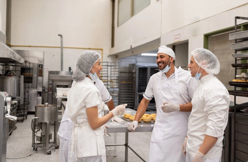 Group of Latin American employees at an industrial bakery talking while taking a break