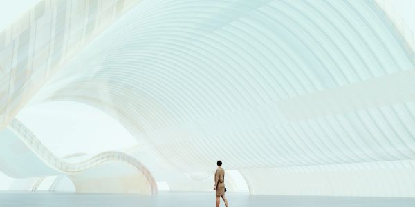 Person standing in a futuristic white architectural space.