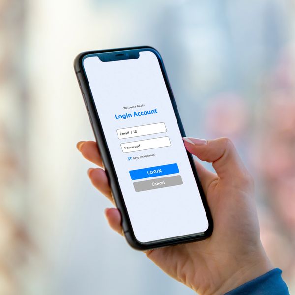 Person holding smartphone displaying a login screen for account access.