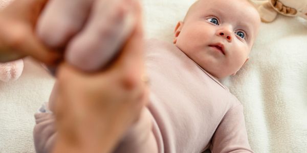 A baby lying down, looking up with curious eyes.