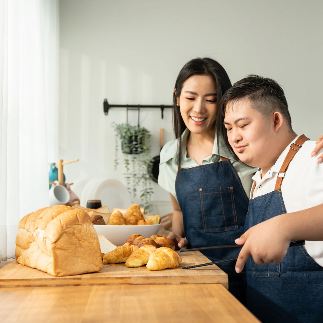 Two people baking and enjoying croissants in the kitchen.