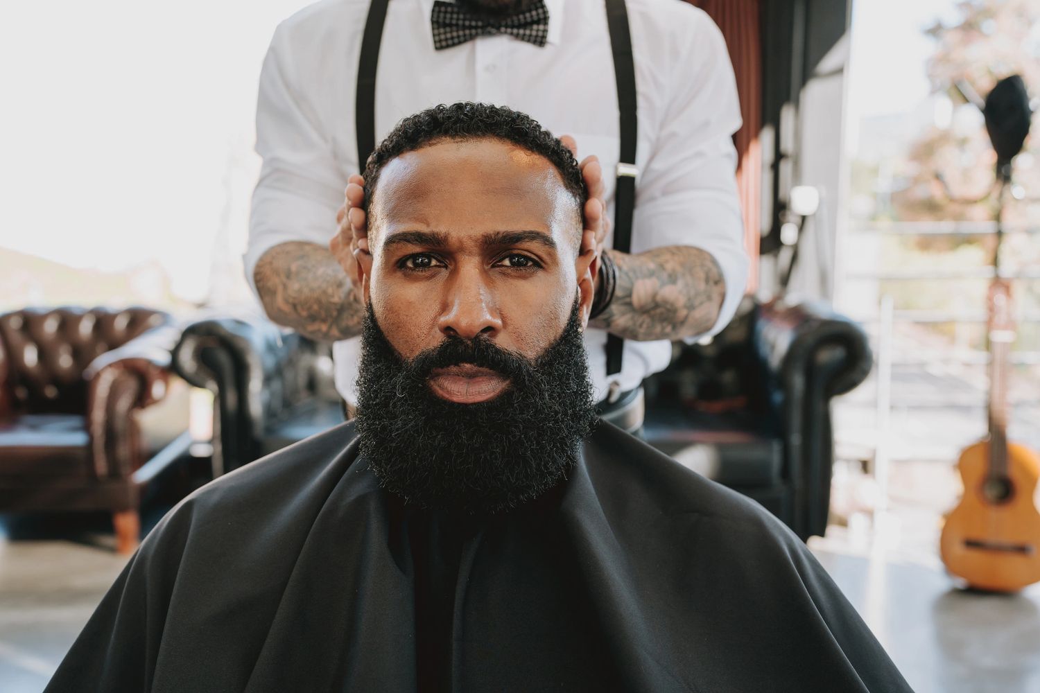Barber styling a man's beard in a vintage barbershop.