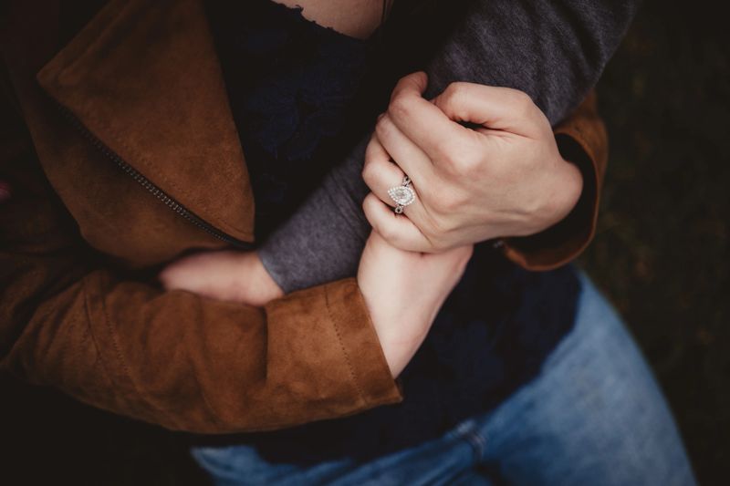 Man and woman holding hands with diamond engagement ring