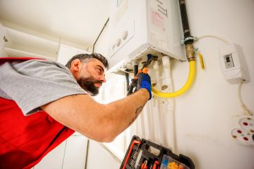 A technician repairs a boiler with pliers.