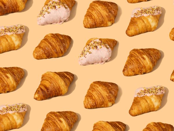 Pattern of croissants with and without pink frosting on beige background.