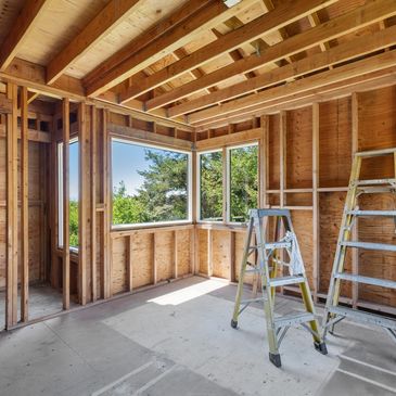 Room under construction with wooden framing and two ladders.