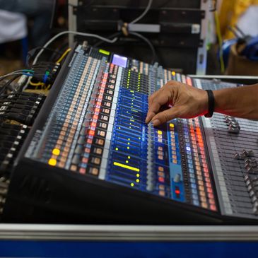 Hand adjusting sound mixer controls.