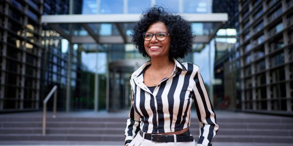 Smiling woman with curly hair and striped shirt outdoors.