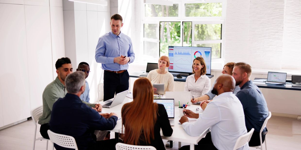 Business team in a meeting room with charts on screens.