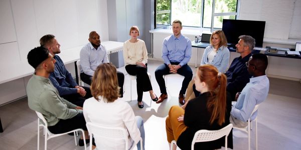 A diverse group of people in a discussion circle during a meeting.