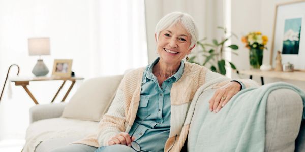 Smiling elderly woman sitting on a cozy couch.
