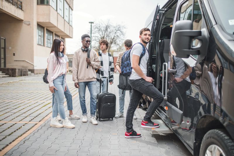 A group of students board a minibus, ready for travel and adventure