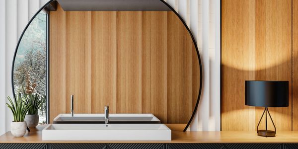 Modern bathroom sink with circular mirror and wooden wall paneling.