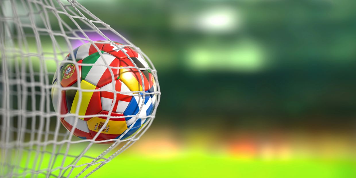 A soccer ball with European flags caught in a net during a game.