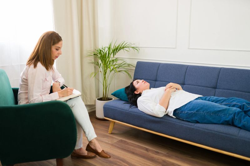 Focused psychologist attentively listens and takes notes while a woman discusses her feelings during a mental health therapy session
