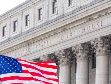 American flag waving outside the United States Courthouse with grand columns.