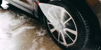 A car tire being cleaned with a high-pressure water spray.