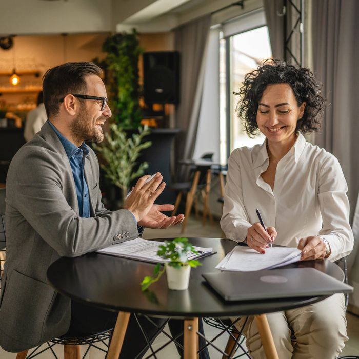Two professionals happily discussing documents at a modern office table.