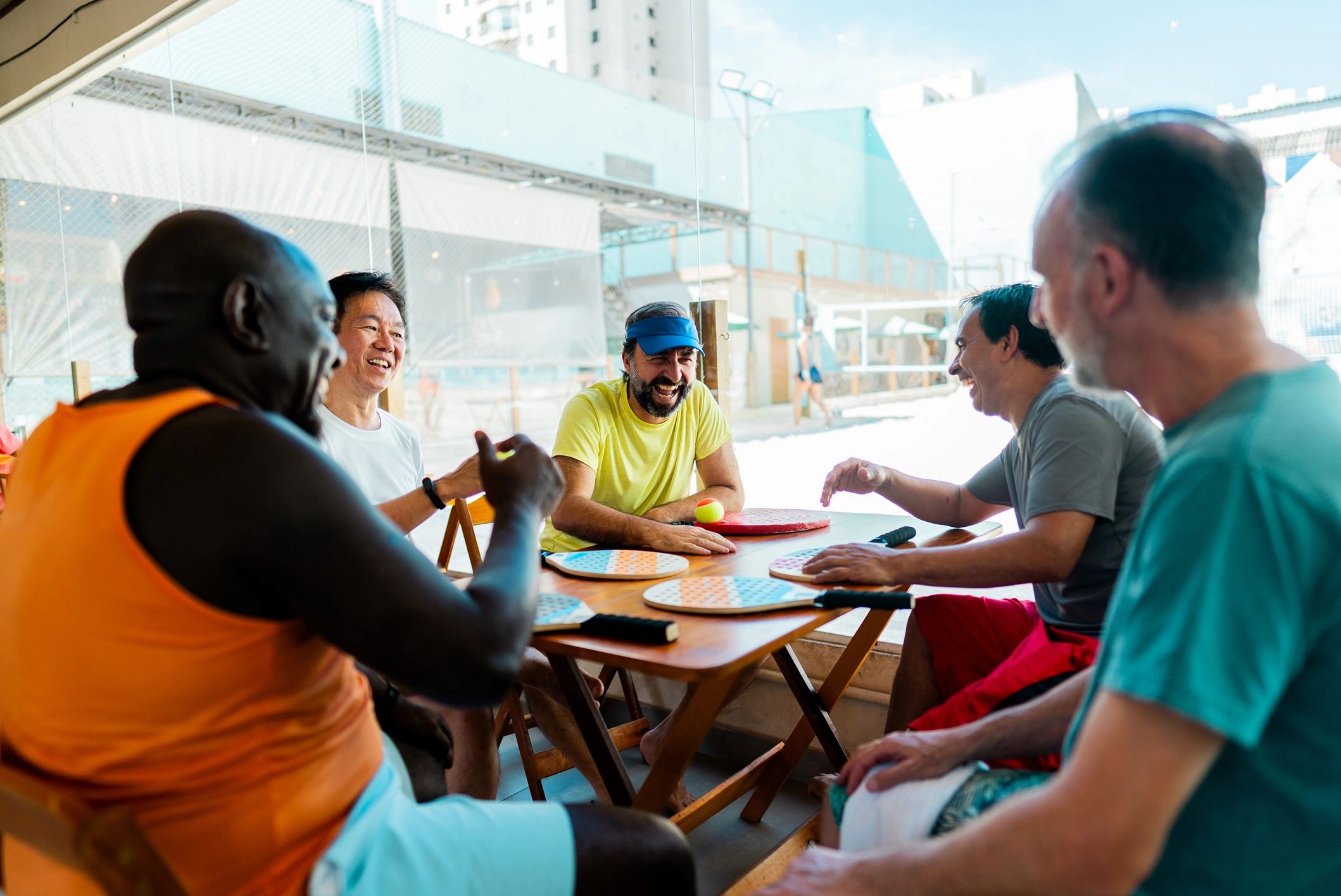 Diverse group of people sitting together around a table, talking and sharing in a bright, welcoming 