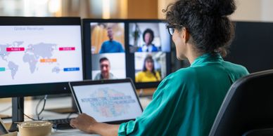 Woman working on laptop with virtual meeting and data charts on screens.