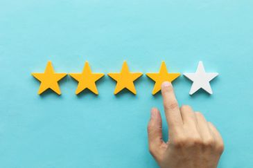 Hand giving a four-star rating out of five on a blue background.