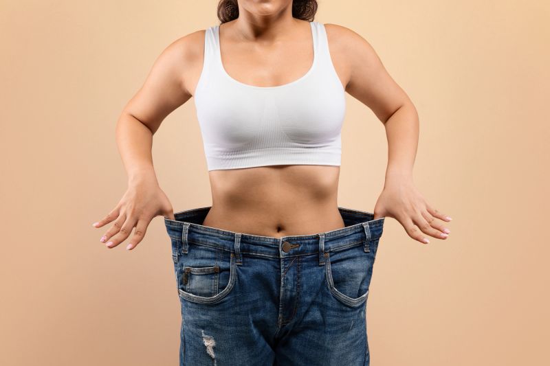Successful diet concept. Cropped shot of young female in big size jeans demonstrating results of her slimming program, unrecognizable woman in oversize clothes comparing body after weight loss