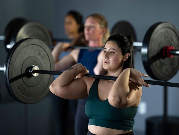 Women lifting barbells in a gym.