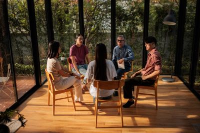 Group of five people having a discussion in a glass-walled room.