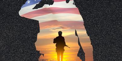 Silhouette of a soldier with American flag and sunset background.