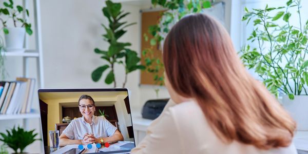 Woman video chatting with a smiling person on a laptop at home.