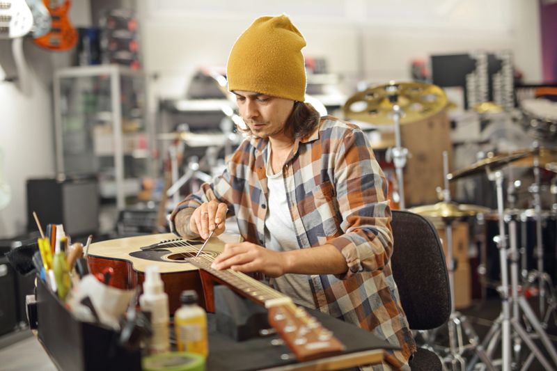 Young man repairing an acoustic guitar in a workshop