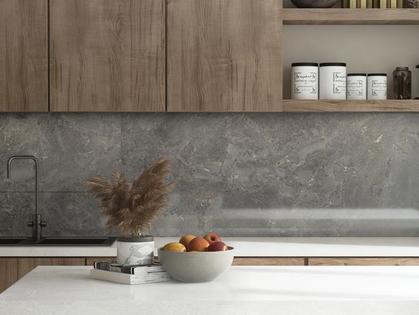 Modern kitchen with wooden cabinets, marble backsplash, and a fruit bowl on the countertop.