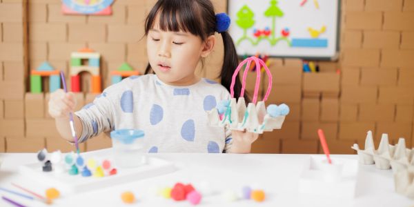 Teacher engaging toddlers in creative play at a colorful daycare.