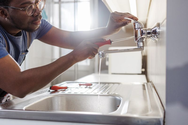 Young African American handyman repairing a sink