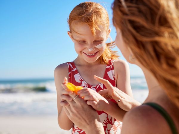 Non-custodial mother enjoying a safe visit on the beach, playing in the sand, with daughter. 