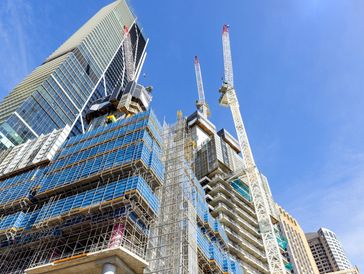 Construction site with cranes and scaffolding on skyscrapers.