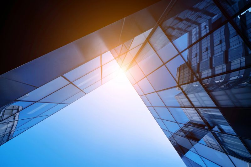 Sunlit modern glass buildings showcasing architectural beauty and urban development against a blue sky.
