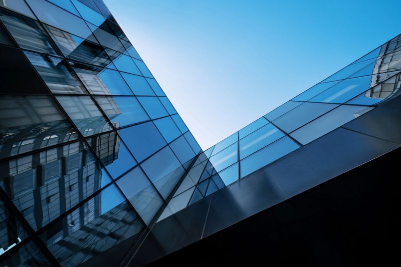 Abstract view of modern glass architecture, reflecting the clear blue sky. Sleek and contemporary design concept.