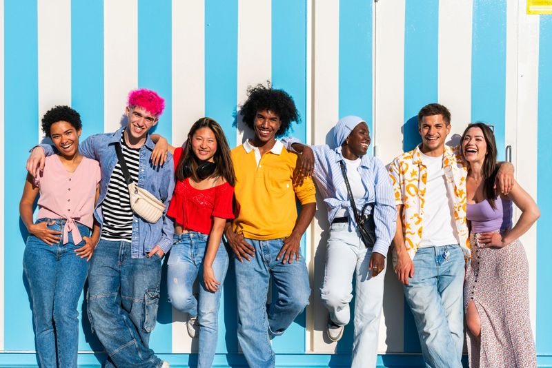 Multiethnic group of young happy friends hanging out in the city - Multiracial group of students meeting and having fun outdoors, concepts about youth, teenage, diversity and lifestyle