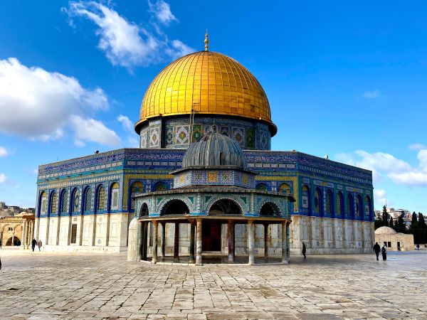 The Dome of the Rock with a golden dome under a blue sky.