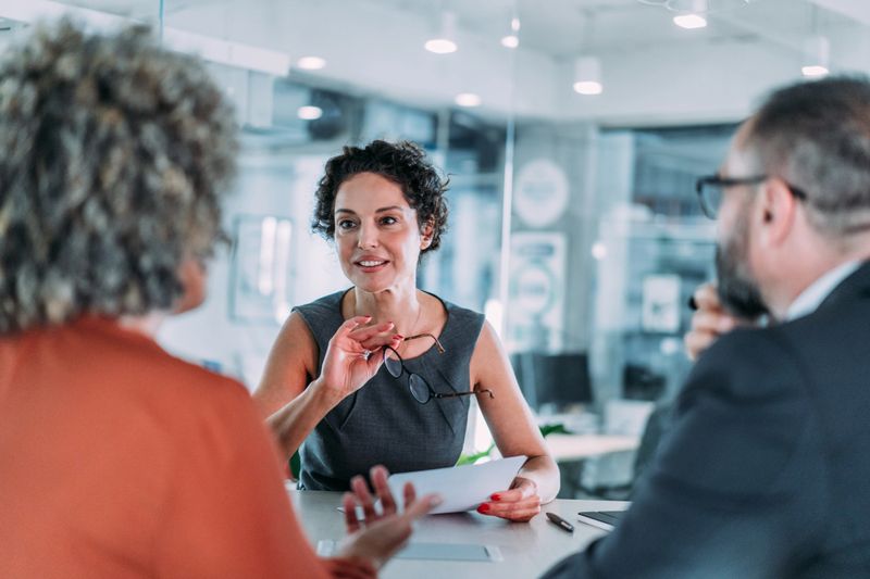 Shot of group of business persons in business meeting. Three entrepreneurs on meeting in board room. Corporate business team on meeting in modern office. Female manager discussing new project with her colleagues. Company owner on a meeting with two of her employees in her office.
