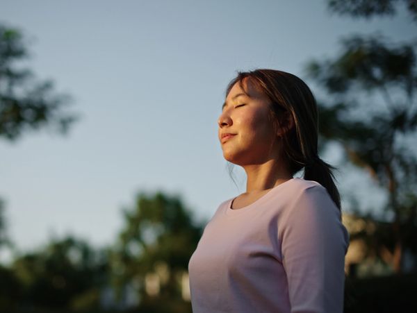 A woman with her eyes closed, feeling the sun on her face.