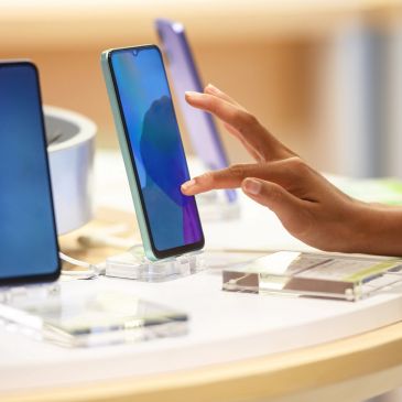 Hand interacting with a smartphone on display at a store.