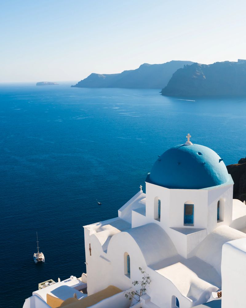 White architecture in Santorini island, Greece. Traditional church with blue dome in Oia town. Beautiful sea view at sunset.