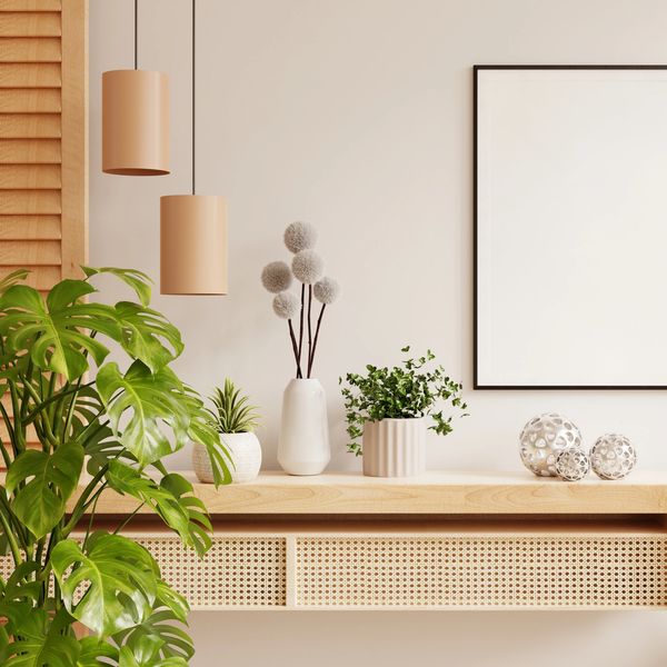 Modern interior with plants, wooden furniture, and blank framed wall art.