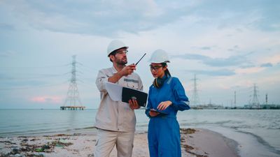 Two engineers inspecting a coastal industrial site during sunset.