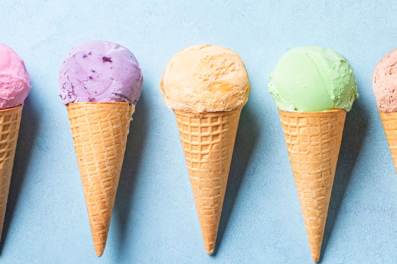 Seven colorful ice cream cones lined up against a blue background.