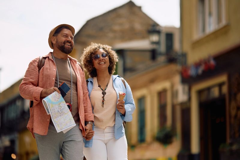 Happy mature couple of tourists holding hands while walking on the street. Copy space.